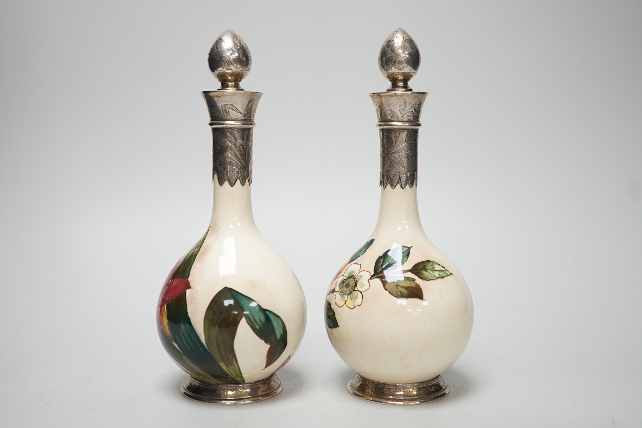 A pair of Victorian silver mounted floral painted earthenware bottle vases. 21cm high